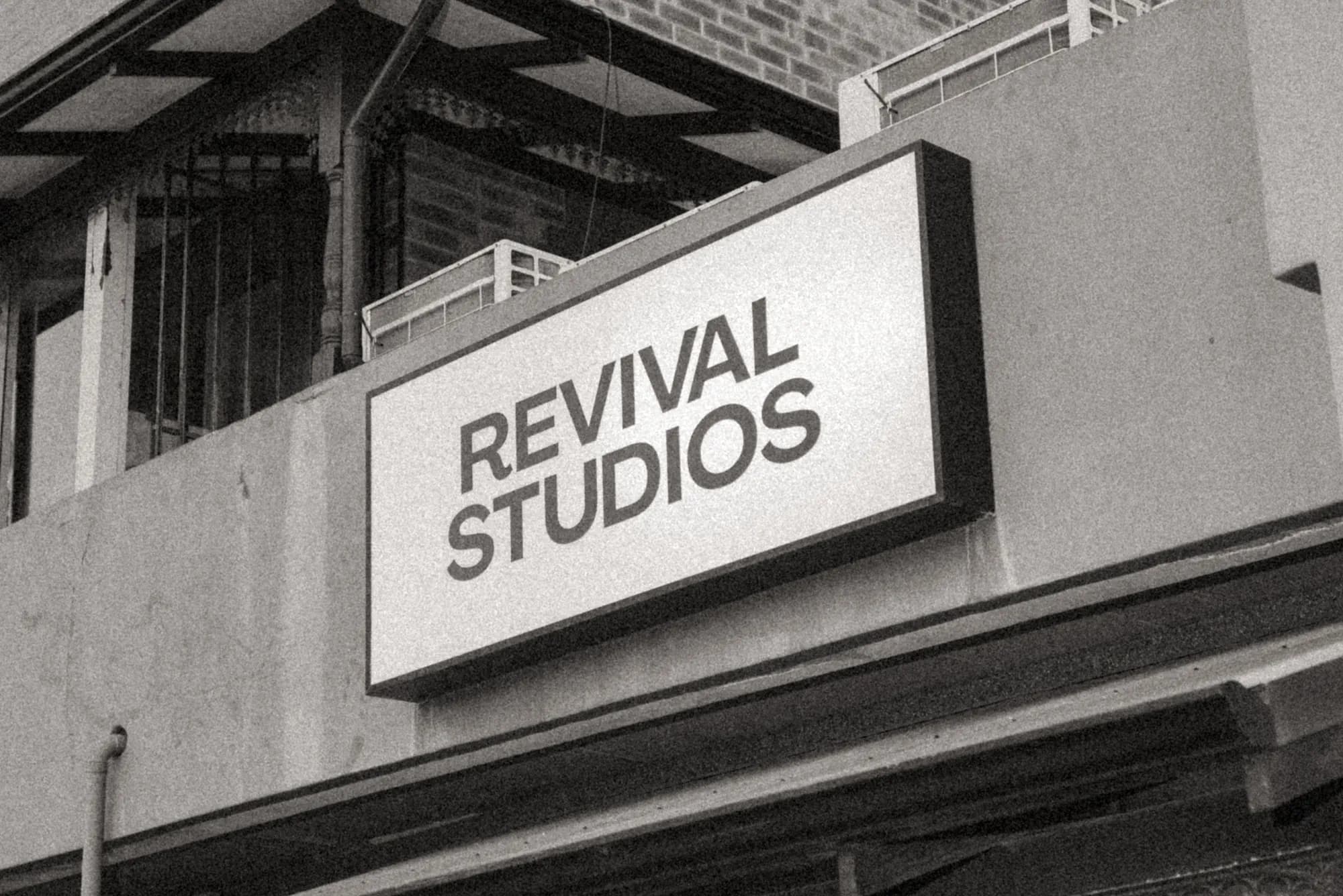The Revival Studios signbox mounted on the building exterior, shot from below in grainy black and white.